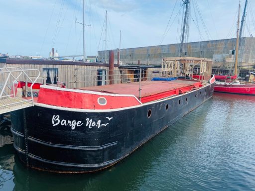 Barge no 9 freshly painted, black hull with red trim. Barge no 9 painted in white on the front, with a gull. In the water at Lake Lothing